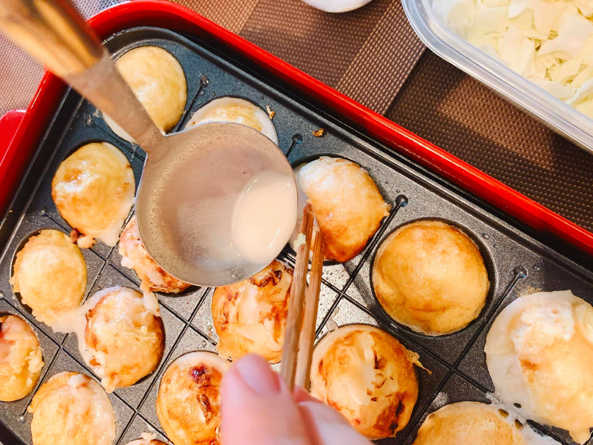 Nướng bánh Takoyaki (múc thêm bột đổ vào từng ô để tạo bánh tròn đẹp mắt)